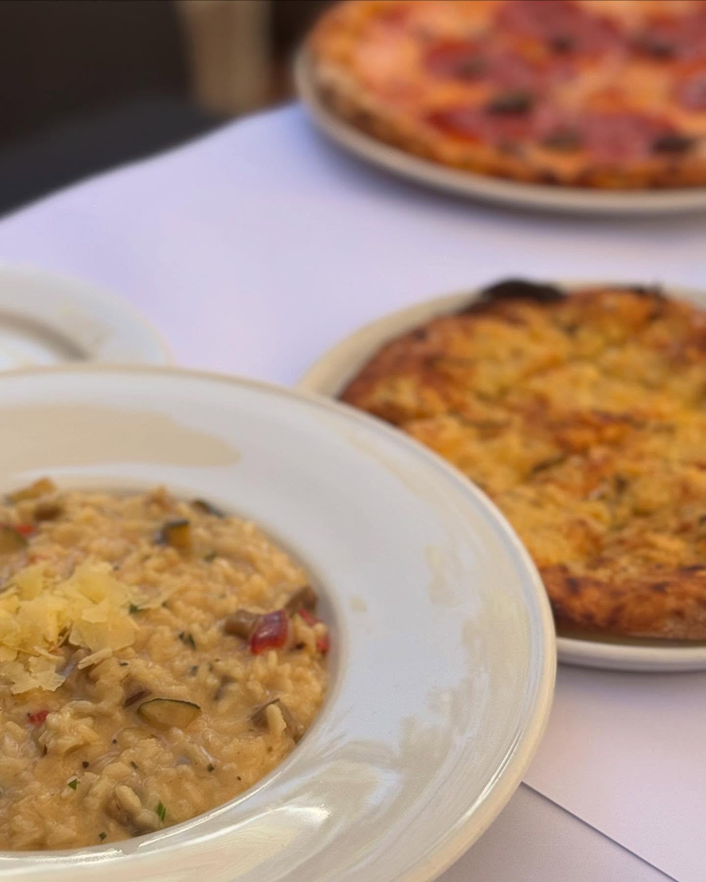 Risotto and a woodfired pizza on a white tablecloth